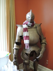 Suit of armor wearing a burgundy and grey scarf.